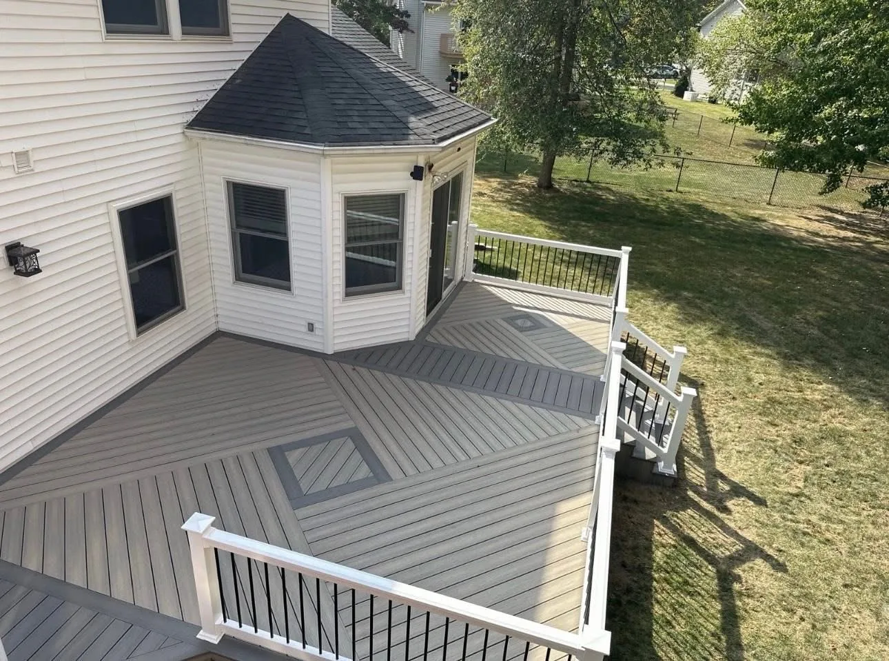 Aerial view of a grey composite deck with white railing and black balusters at a white home