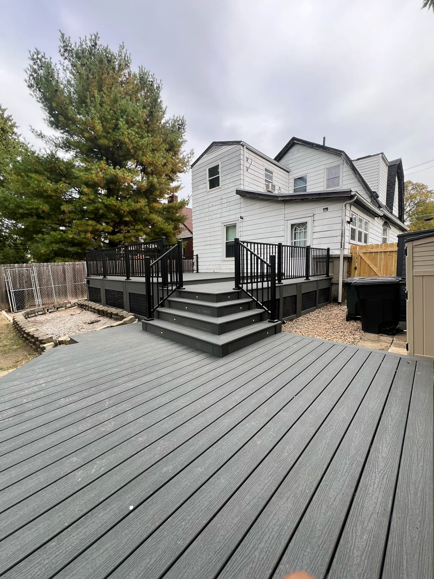 Grey composite deck boards and steps with black borders at a white sided home