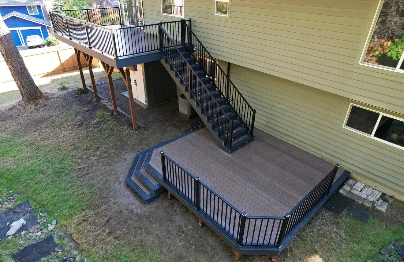 Aerial view of a grey composite deck and black staircase at a green sided home