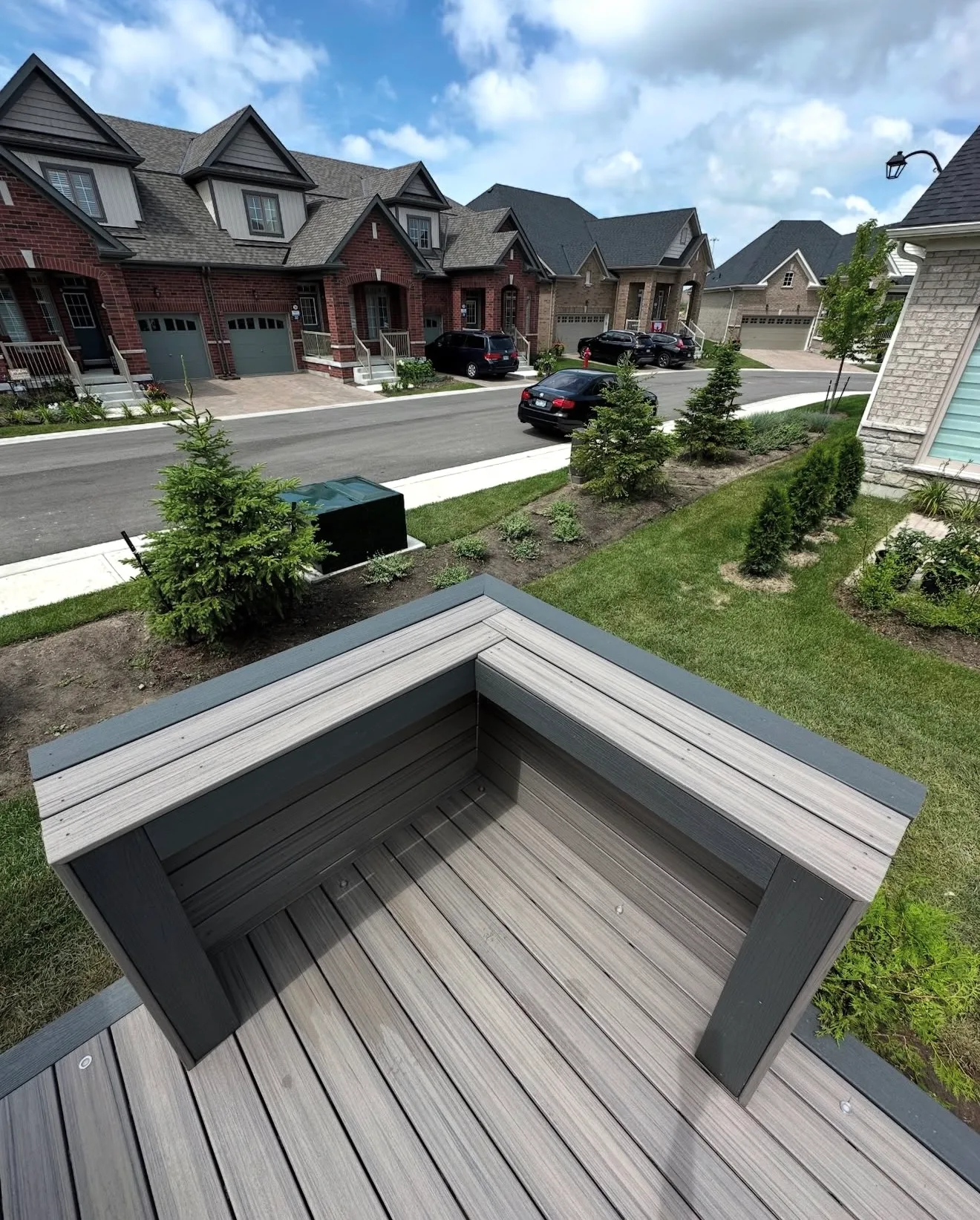 Grey composite deck with a corner bench seat near a residential street