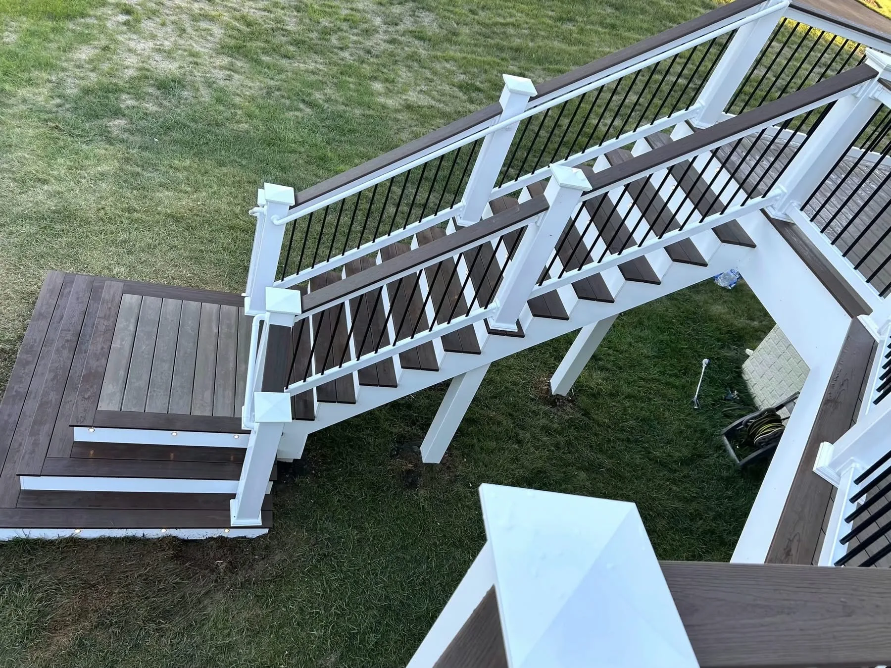 Aerial view of a white composite staircase and deck landing on a green lawn