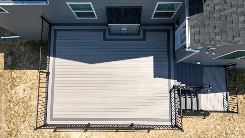 Overhead view of a grey composite deck with cable railing against a dark sided home