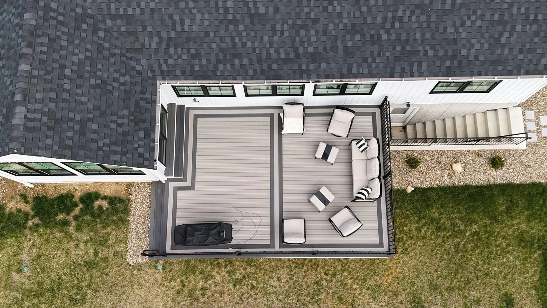 Overhead view of a grey composite deck with lounge furniture at a shingled home