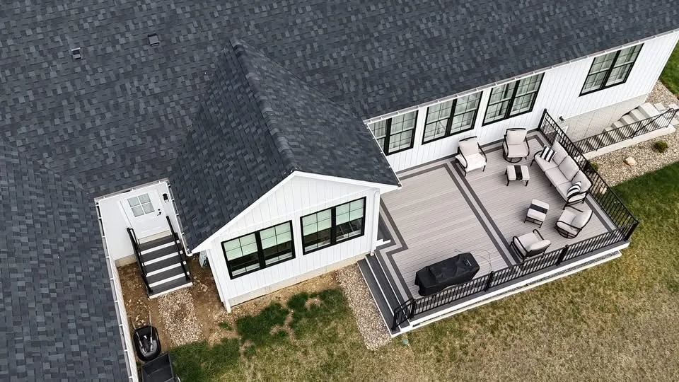 Aerial view of a grey composite deck with lounge seating at a white modern farmhouse