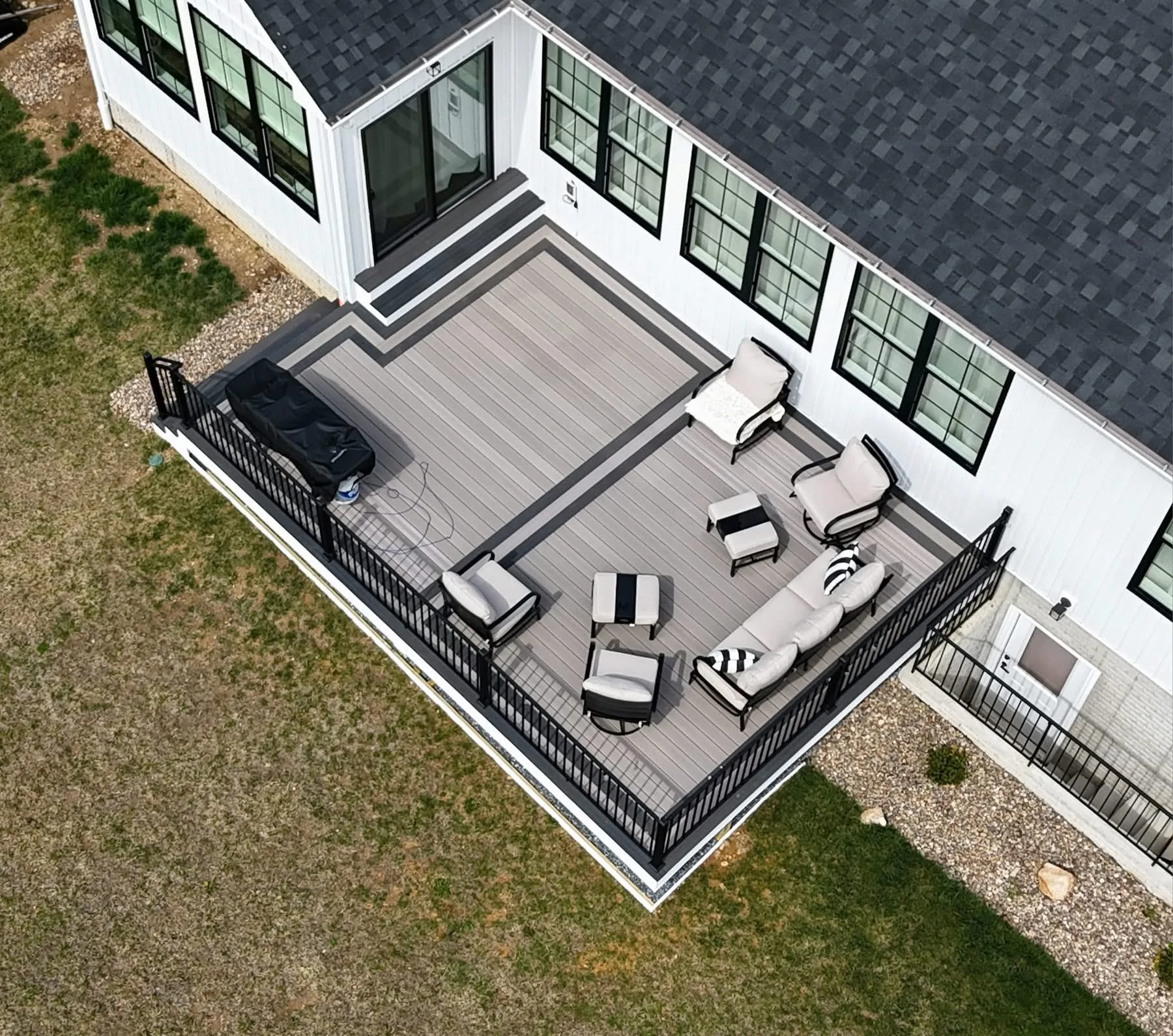 Aerial view of a grey composite deck wrapping a white modern home with lounge furniture