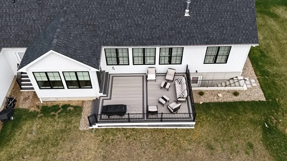 Aerial view of a grey composite deck with seating at the rear of a white modern home