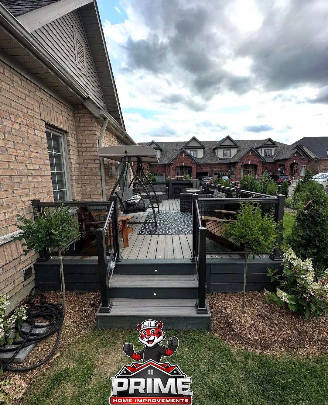 Grey composite deck with steps and planters at a brick home